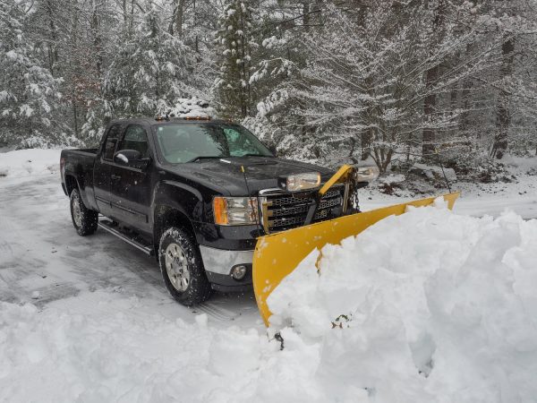 Truck snow plow clearing a parking lot after storm